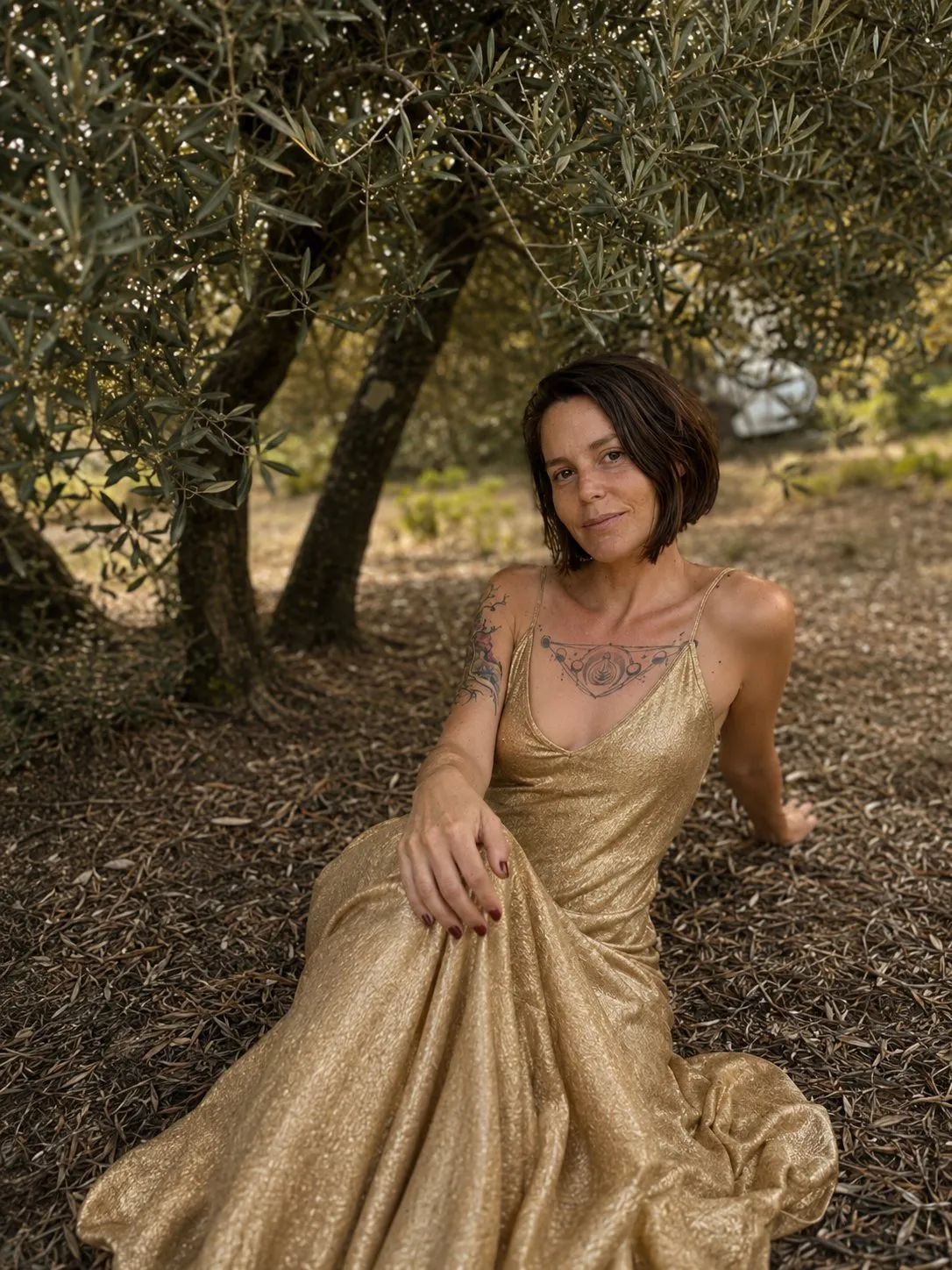 María Catalina Fernández, vestida de dorado, bajo un olivo